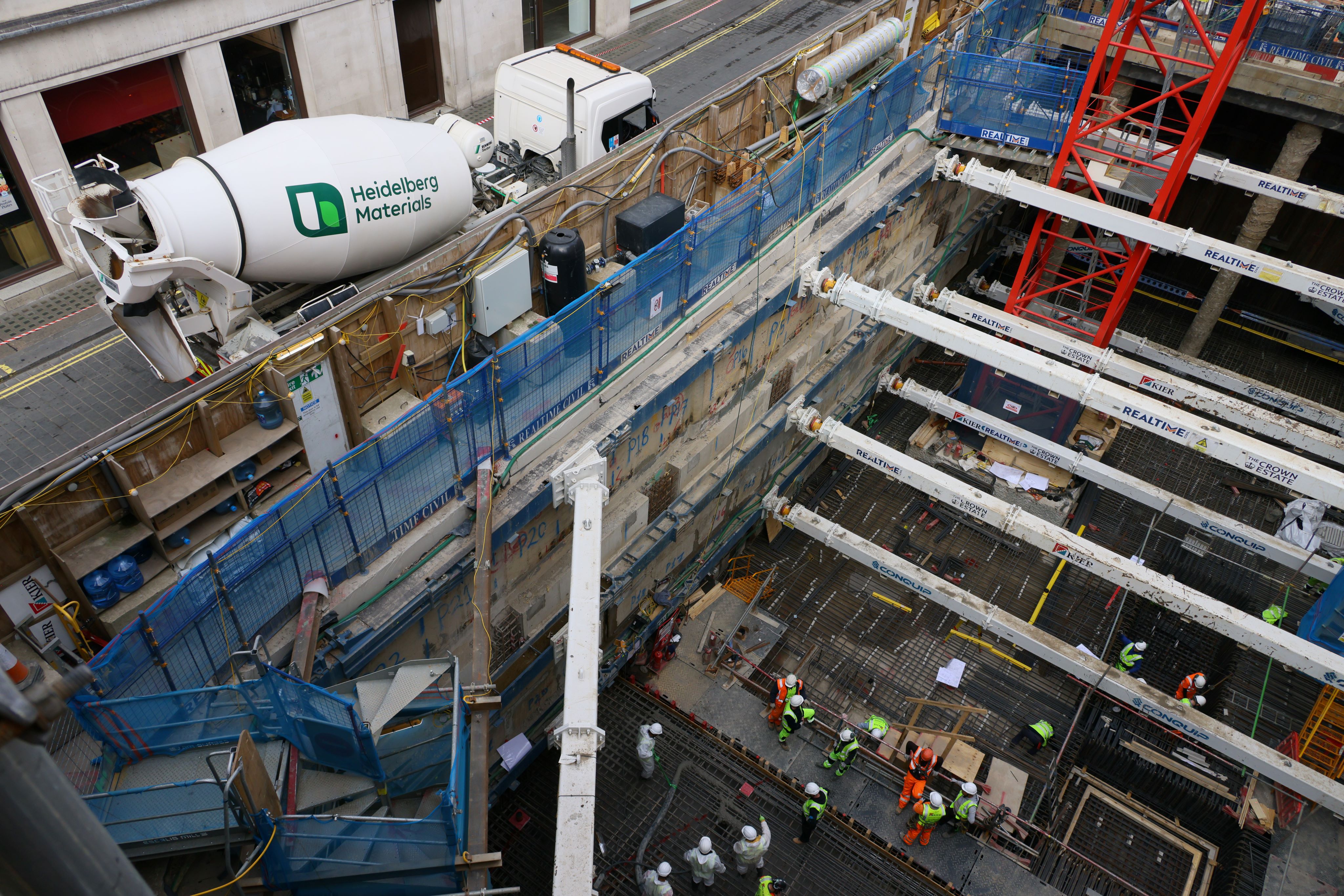 A construction site with workers, scaffolding, and a Heidelberg Materials ready-mixed concrete truck in the background.