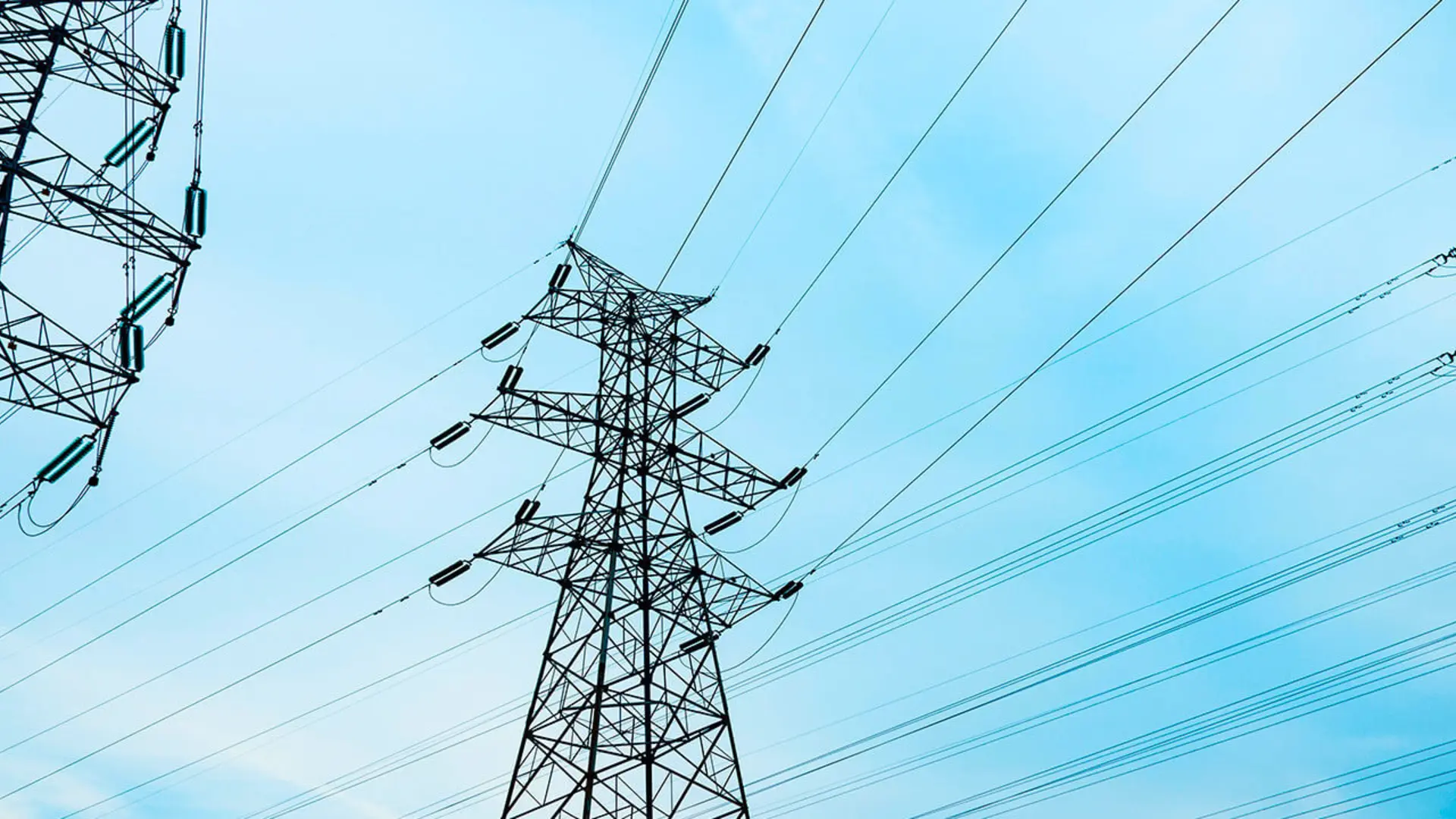 Tall electricity pylons and power lines against a clear blue sky.