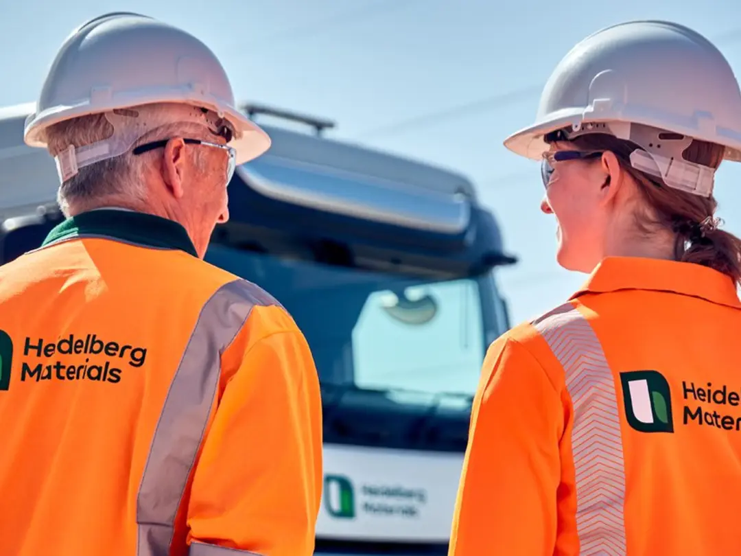 Three workers with jackets with a Heidelberg Materials logo on their back